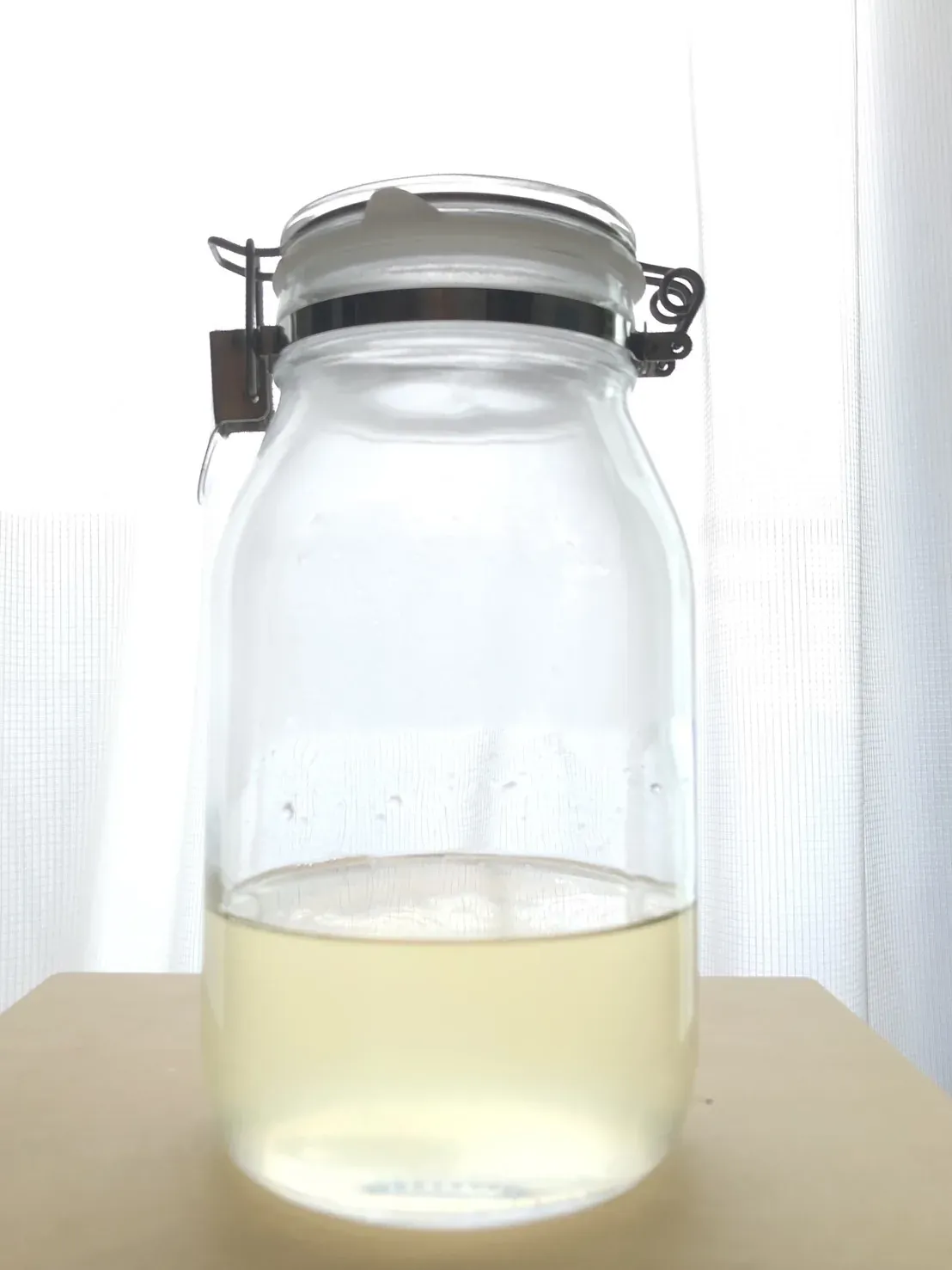 A tall glass jar holding only pale golden umeshu, the plums removed