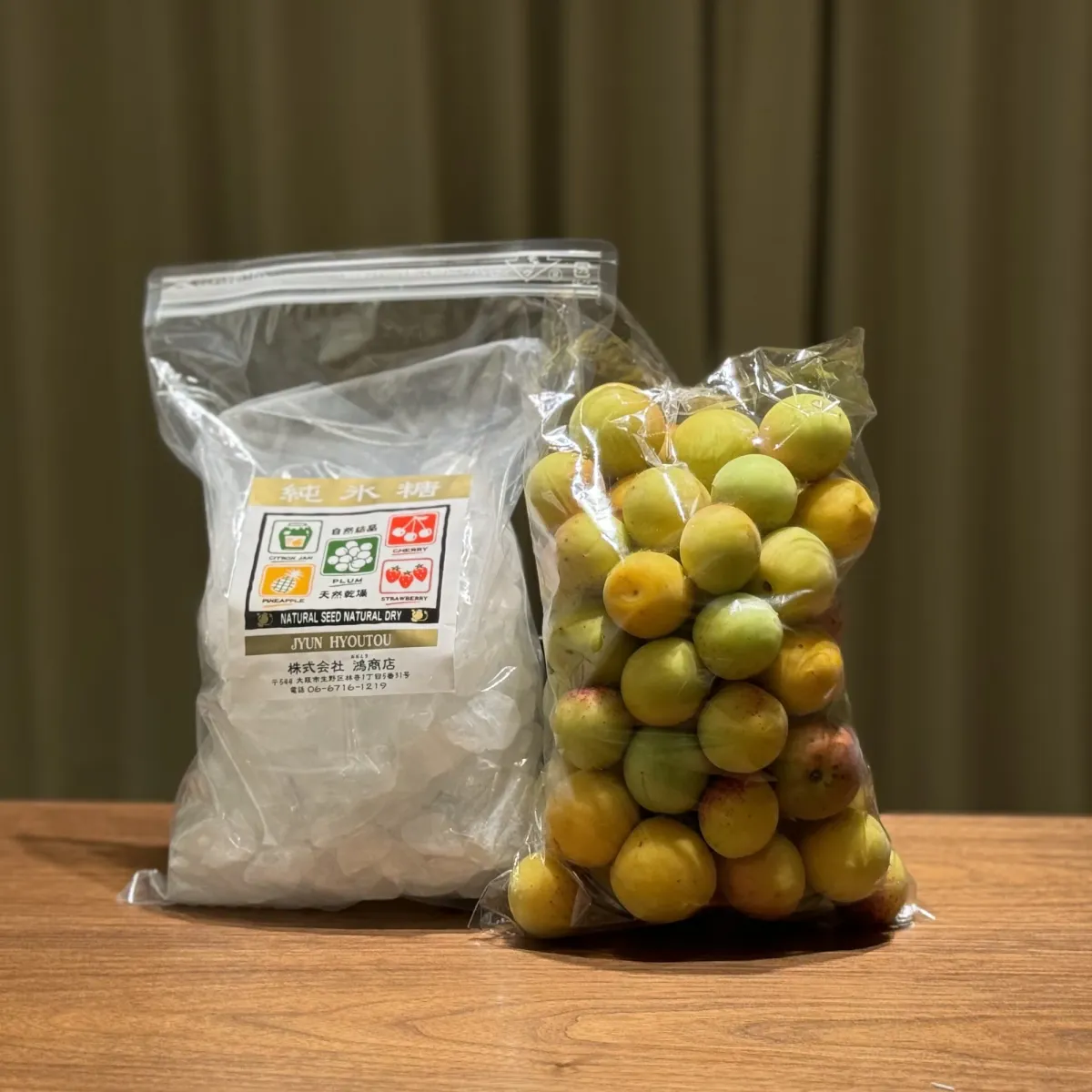Green ume plums beside a clear bag of rock sugar